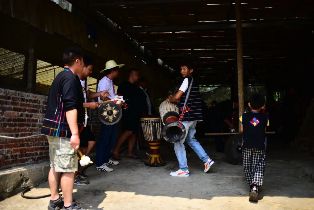 Four people wearing Hani ethnic costumes are performing with musical instruments