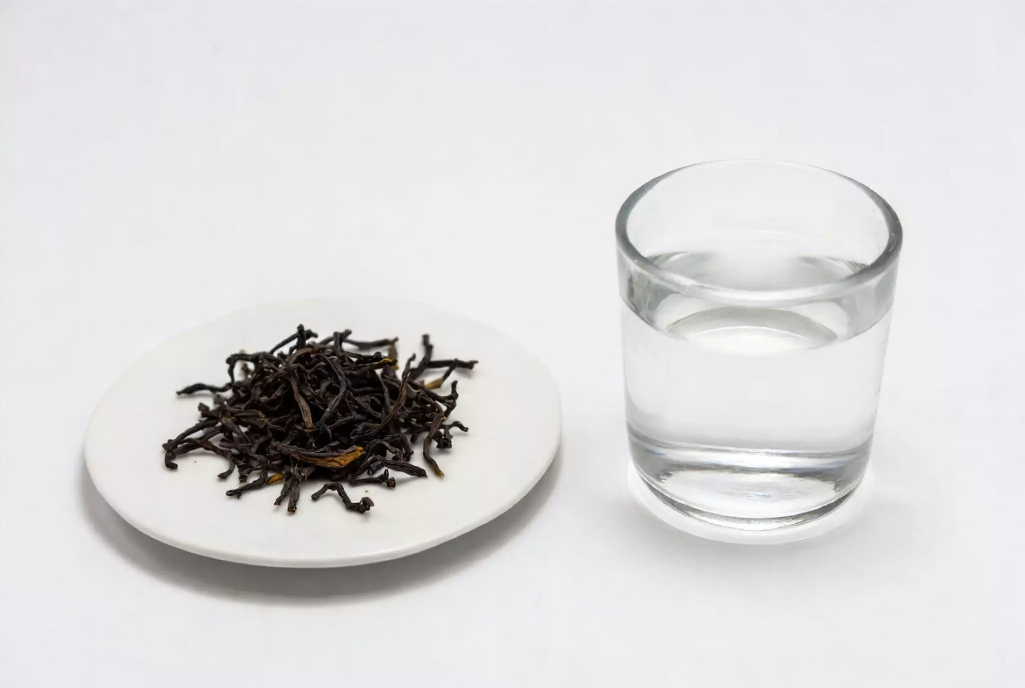 a white ceramic plate holding exactly 3 grams of premium long-leaf raw Pu-erh tea. Next to it, a 300ml glass of clear water.