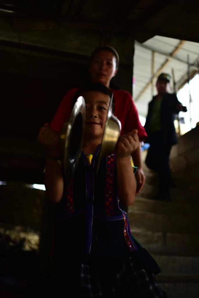A little boy wearing Hani national costume holding a musical instrument in his hand