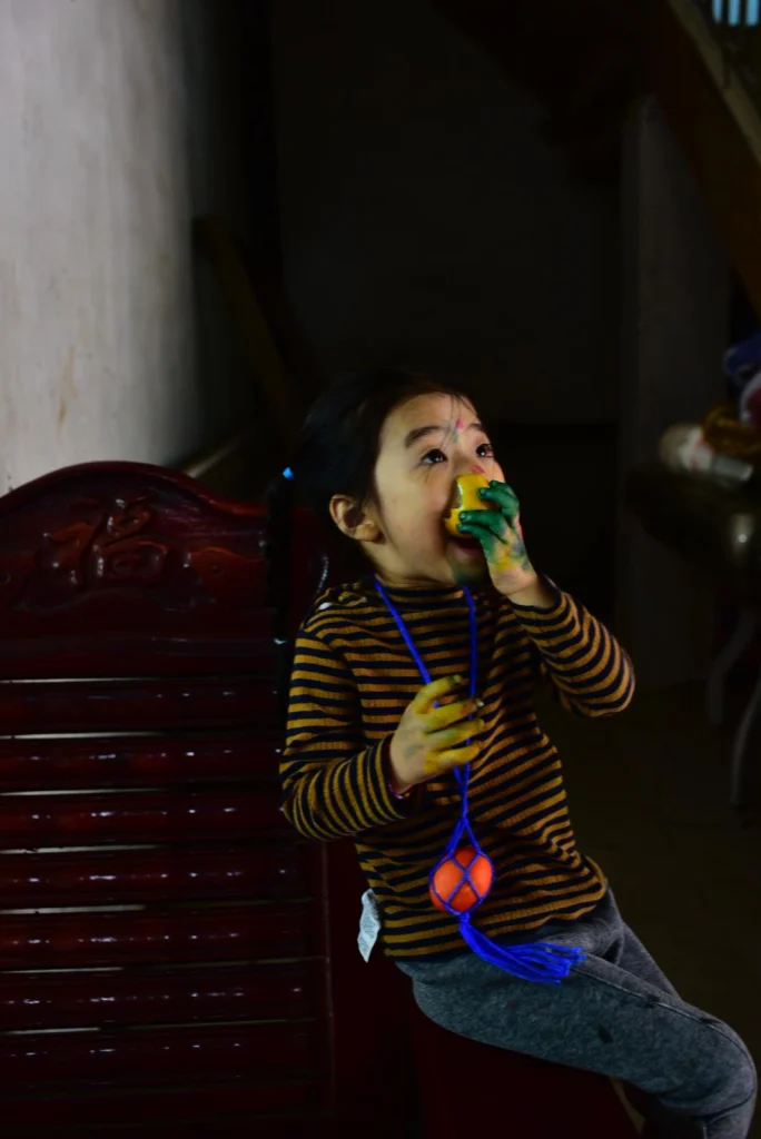 A child eating Easter eggs, with a red Easter egg hanging on his chest