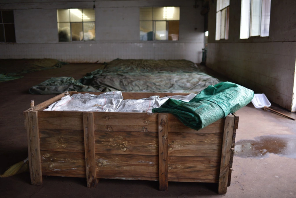 Tea leaves fermented in wooden boxes (off-ground method) to ensure precise humidity control. / 使用木箱进行的离地发酵，确保精准的湿度控制。