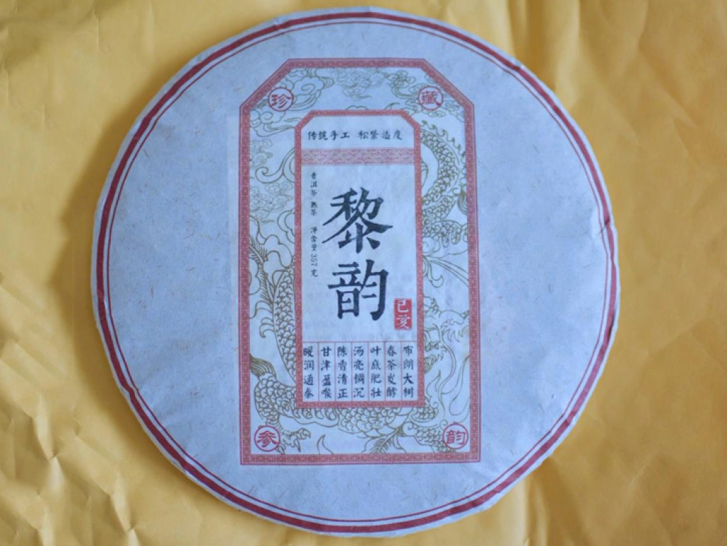 A high-resolution photo of the 'Li Yun' Ripe Pu-erh tea cake, showing the artistic golden-brown leaves. / 《黎韵》熟普洱茶饼特写，展示其金褐相间的茶条。
