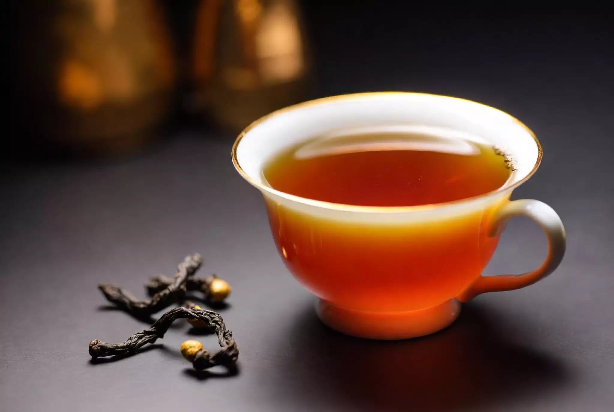 Brewed Yunnan Dianhong black tea soup, rich golden-amber liquor in gaiwan with bright red hue and golden rim