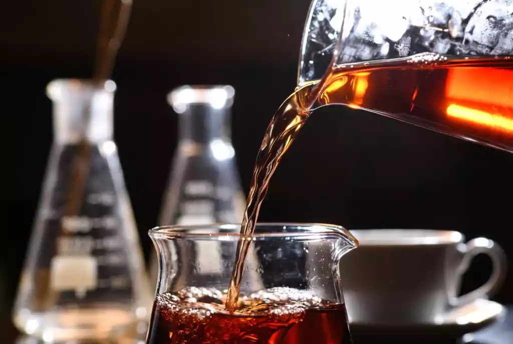 Cinematic close-up of amber-red Chinese tea being poured from a glass Gaiwan, symbolizing the science-backed tea ritual