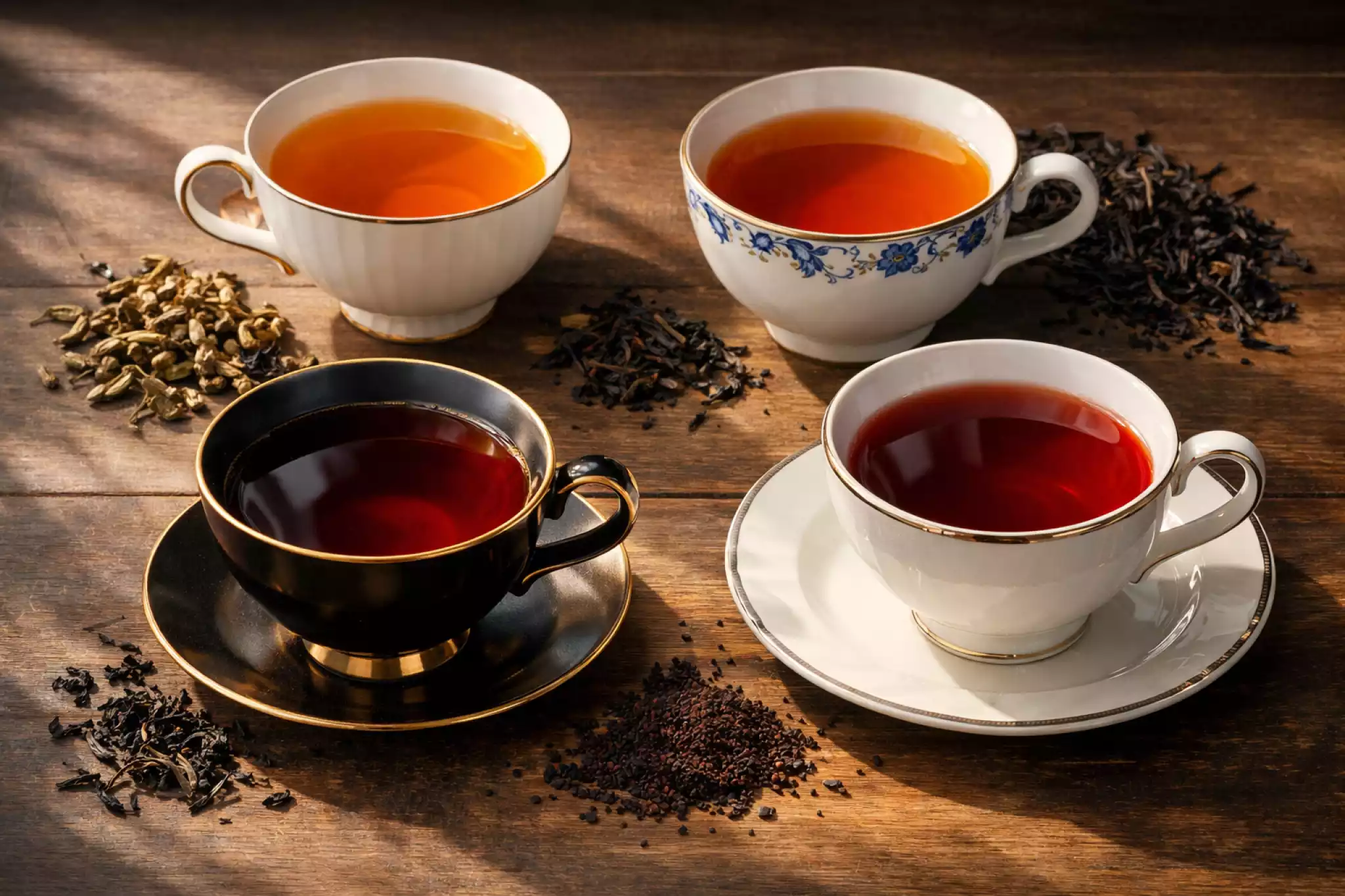 Various black tea liquors in porcelain cups ranging from amber to ruby red