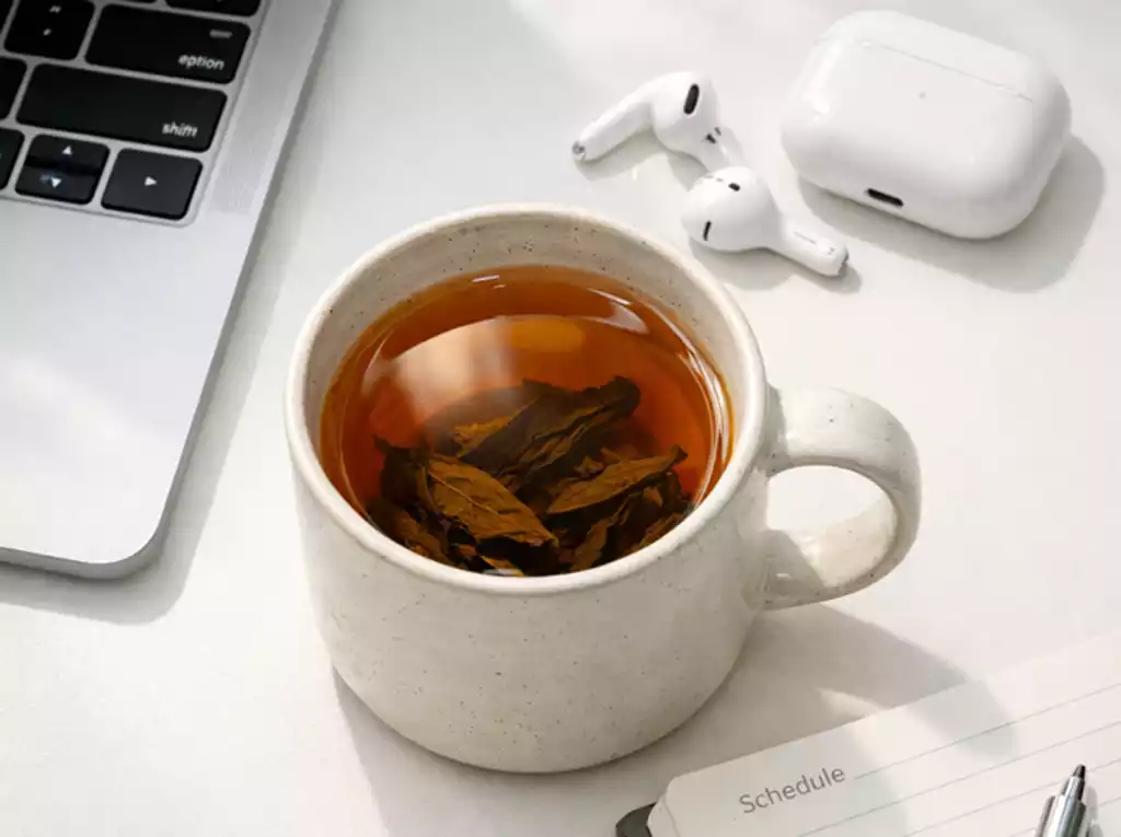 Steeping loose leaf tea in a ceramic mug within an office setting