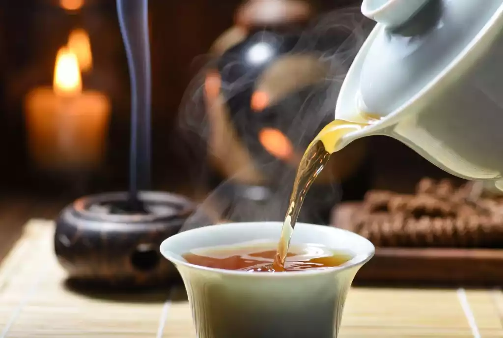 A serene Gongfu tea brewing session with steam rising from a white porcelain Gaiwan
