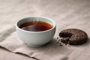 A traditional 357g Pu-erh tea cake alongside a modern glass server, showcasing the contrast between heritage and contemporary brewing.