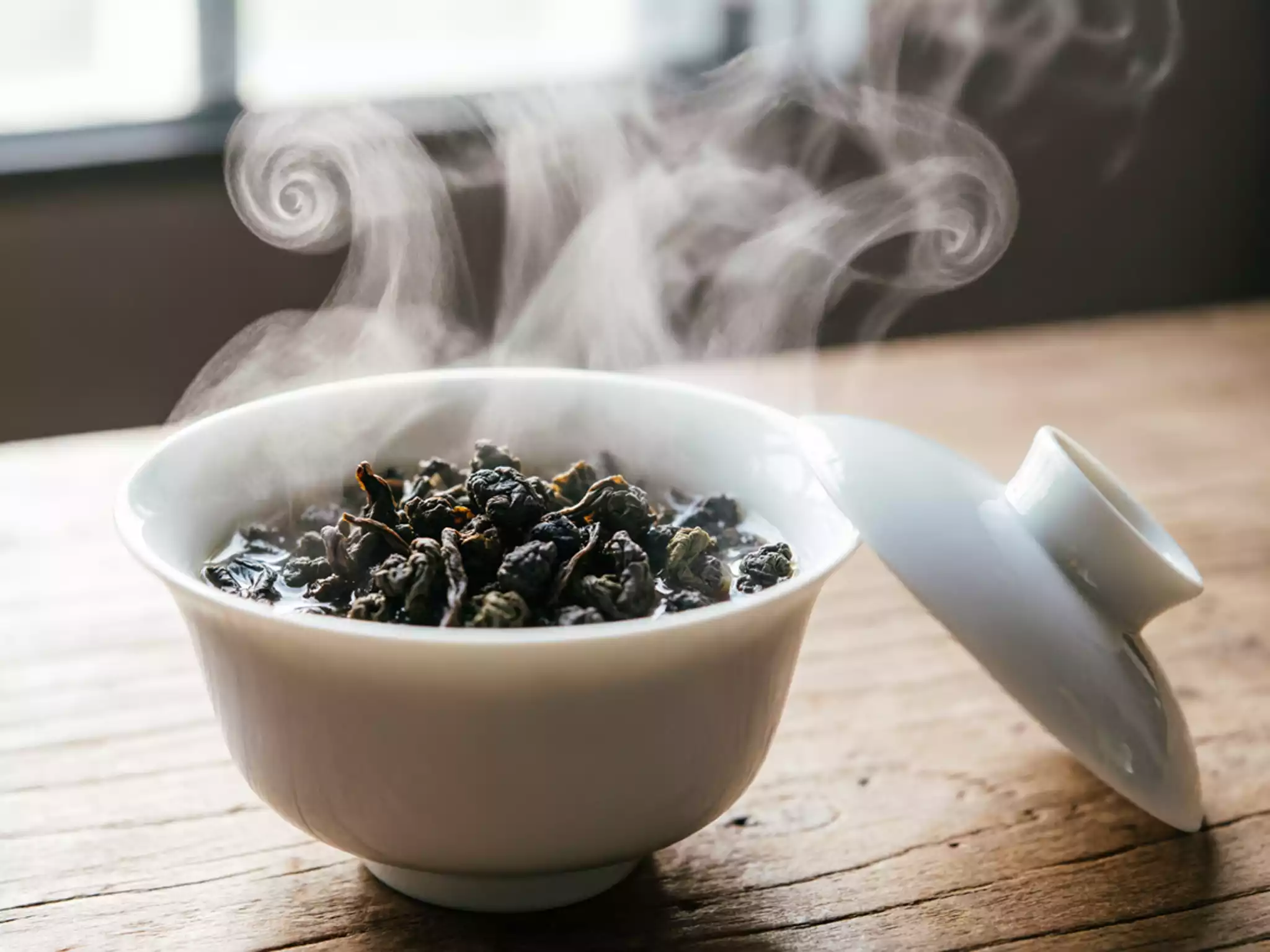 Steam rising from a ceramic gaiwan brewing roasted Oolong tea, illustrating tea aroma and relaxation