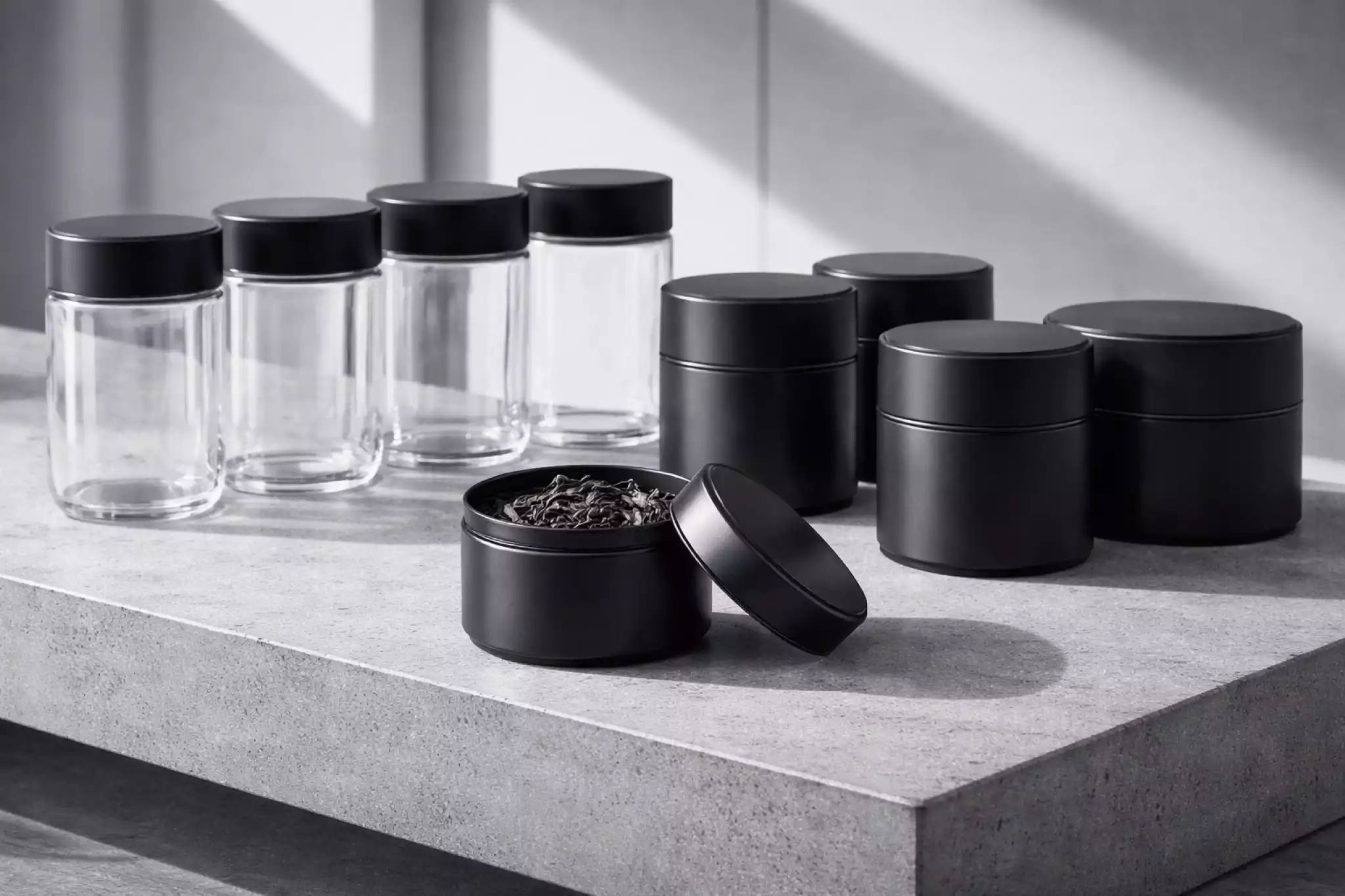 Tiered storage of black metal tea canisters on an industrial concrete shelf