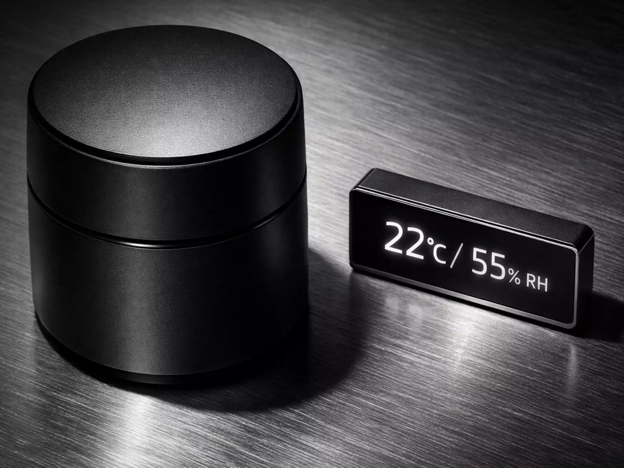 Matte black double-lid tea canister on brushed titanium surface representing airtight professional storage